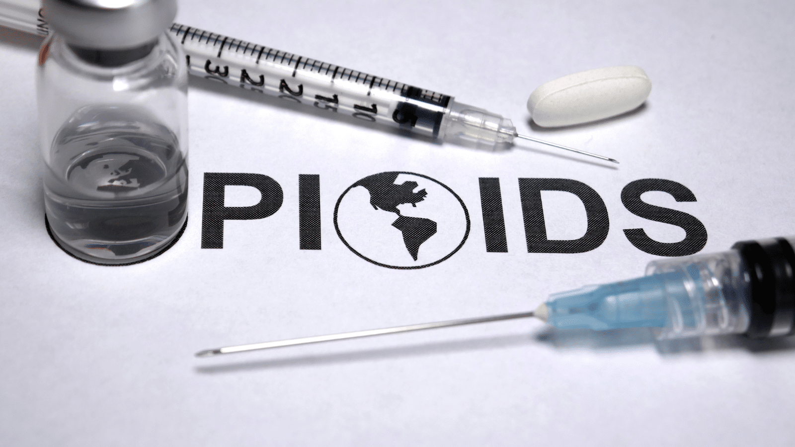 A vial, a tablet, and two syringes are placed around the word OPIOIDS, with the letter O deted as a globe, highlighting the global opioid crisis.