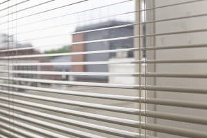 open window blinds show view of a blurred street in the background