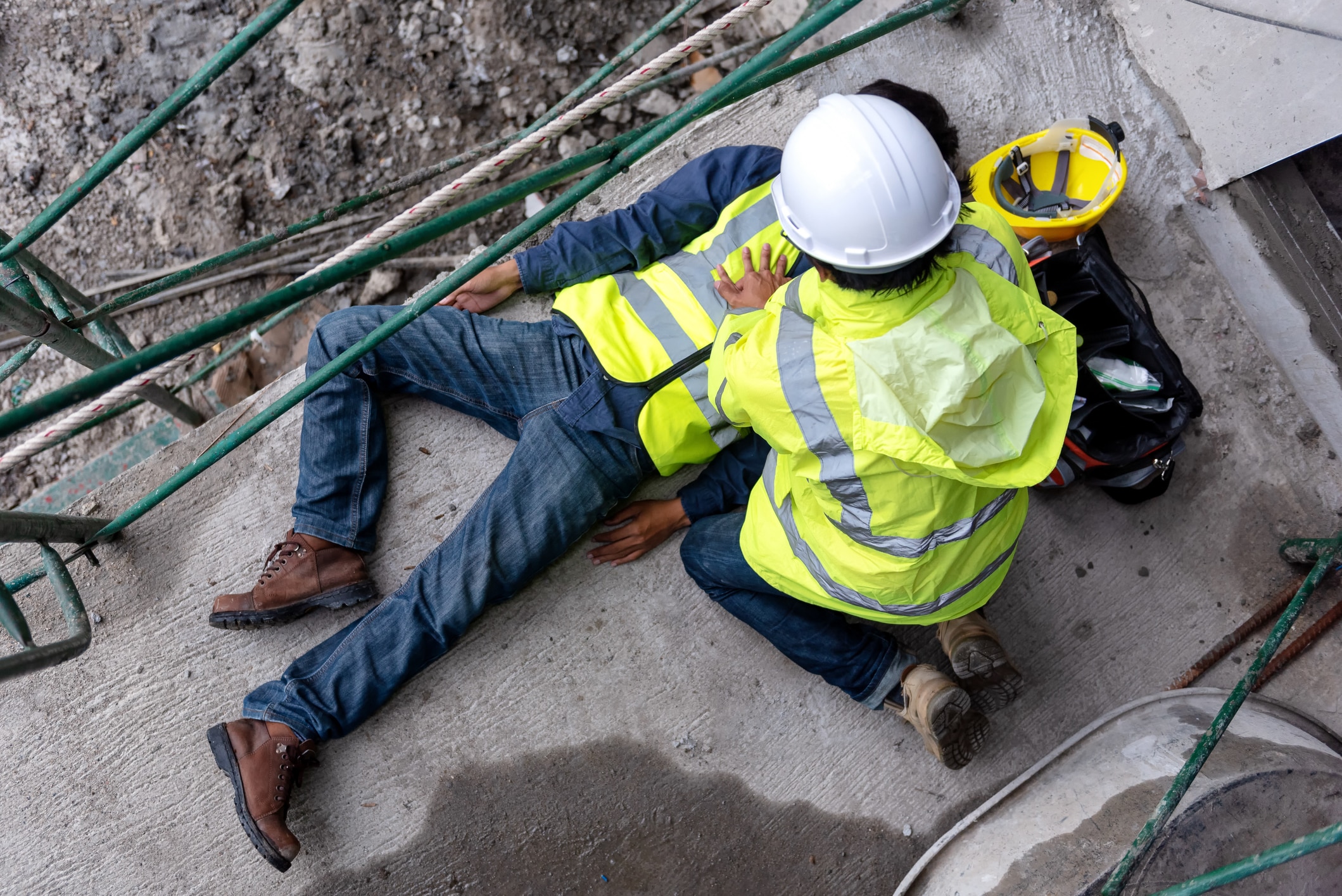 First aid support accident at work of construction worker at site. Builder accident falls scaffolding on floor, Safety team helps employee accident.