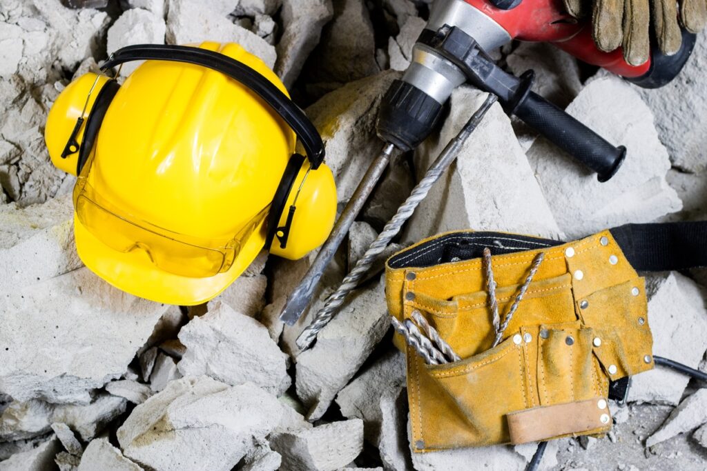 Demolition of walls. Electric hammer helmet and hearing protection lying on the rubble. Old brick and remodeled building wall. Grunt on the background of the old wall.