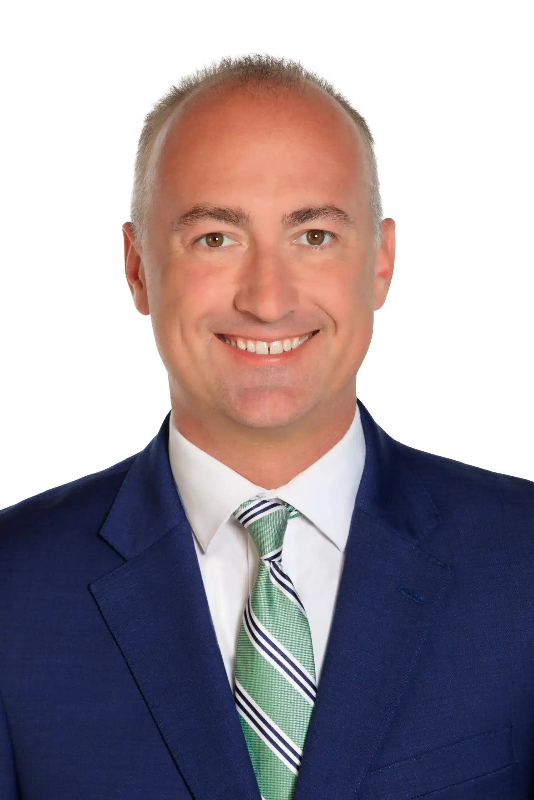 A man with short gray hair wearing a blue suit jacket, white dress shirt, and green striped tie, smiling at the camera against a plain white background.
